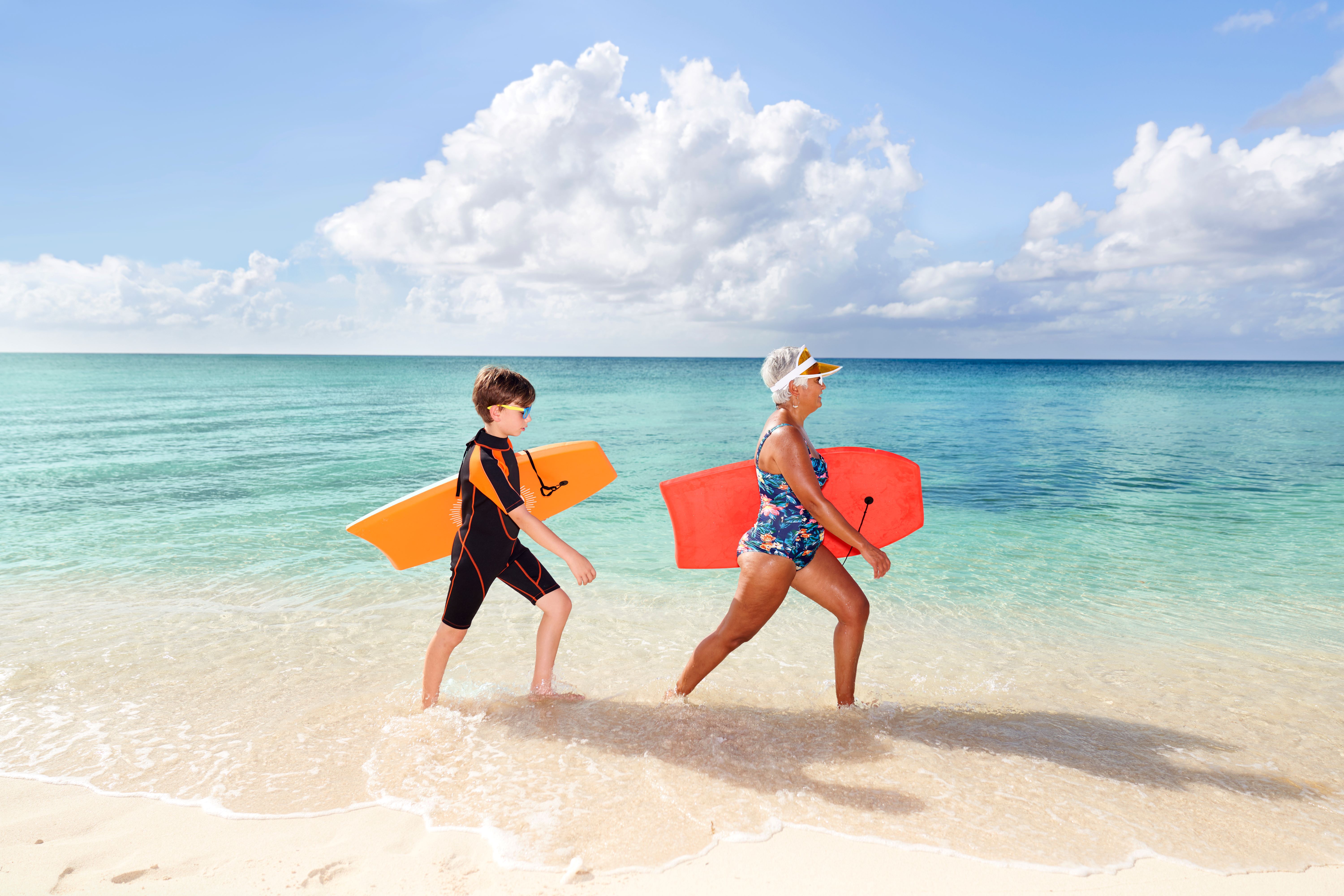 Grandma and Grandson walking in water with boogie boards